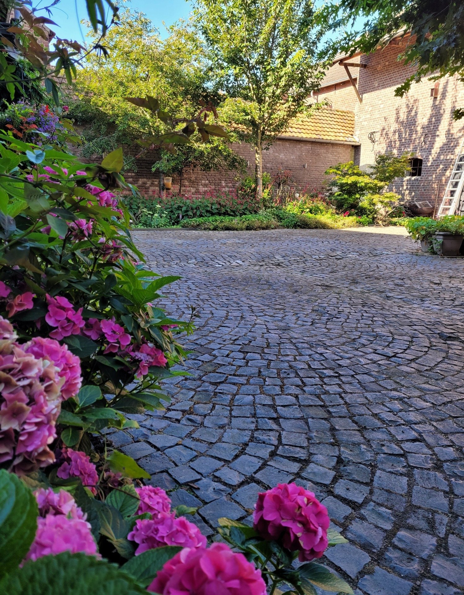 Bloemrijke binnenplaats van Bonvert met de oude boerderij